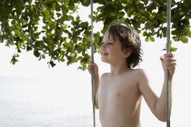 Мальчик стоит на качелях — стоковое фото