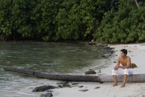 Человек сидит на рухнувшей пальме — стоковое фото