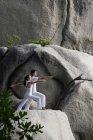 Pareja haciendo yoga sobre roca - foto de stock