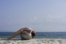 Frau im Bikini auf Ball liegend — Stockfoto