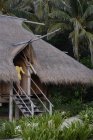 Femme entrant dans la maison tropicale — Photo de stock
