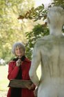 Mujer mayor ponderando estatua - foto de stock