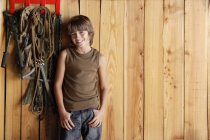 Boy leaning against stable wall — Stock Photo