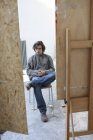 Junger Mann sitzt im Kunstatelier — Stockfoto