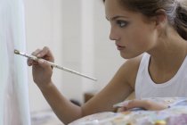 Jeune femme travaillant sur la peinture — Photo de stock