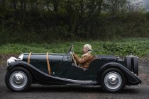 Mulher sênior dirigindo carro antigo — Fotografia de Stock