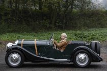 Senior femme conduite voiture antique — Photo de stock