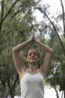 Woman doing yoga exercises under trees — Stock Photo