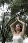 Mulher fazendo exercícios de ioga sob árvores — Fotografia de Stock