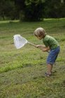 Niño sosteniendo red de mariposa - foto de stock