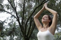Mujer haciendo ejercicios de yoga bajo los árboles - foto de stock