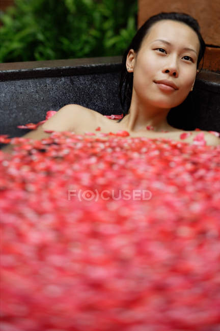 Mulher na banheira com pétalas de rosa — Fotografia de Stock