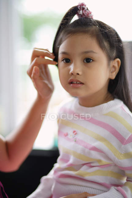 Дівчина дивиться геть, поки мати торкається волосся — стокове фото