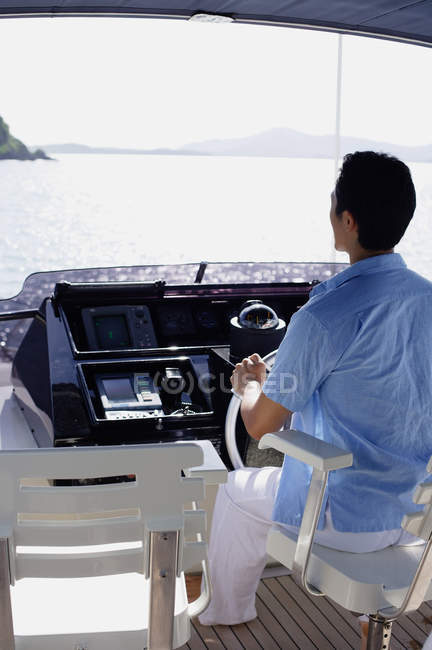 Man in blue shirt steering yacht — Stock Photo