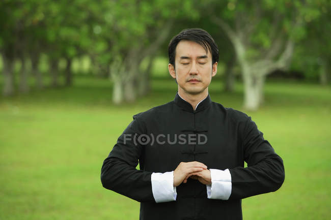 Hombre en kimono practicando meditación - foto de stock