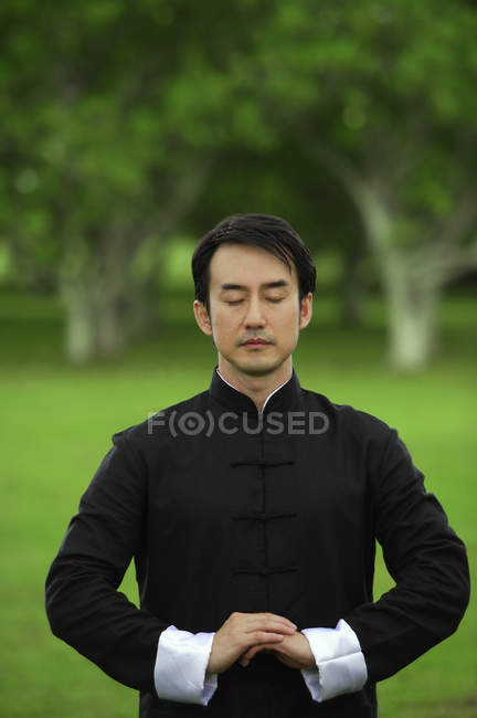 Hombre en kimono practicando meditación - foto de stock