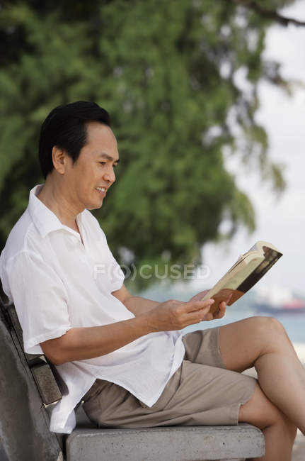 Uomo in spiaggia libro di lettura — Foto stock