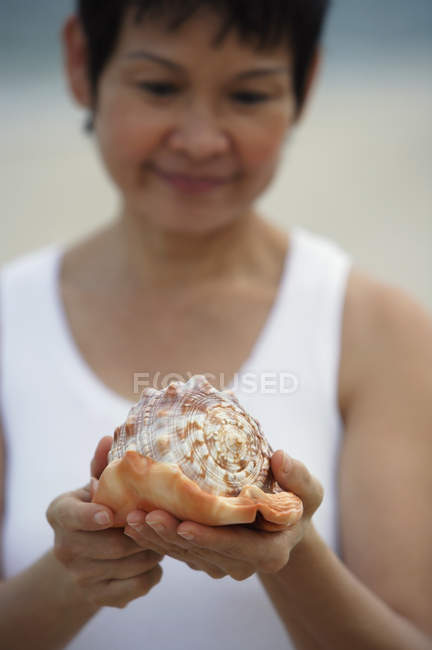 Жінка тримає морську мушлю — стокове фото