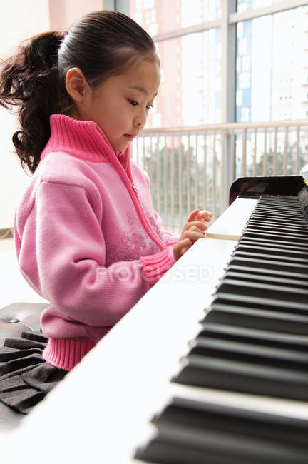 Girl learning to play piano — Stock Photo