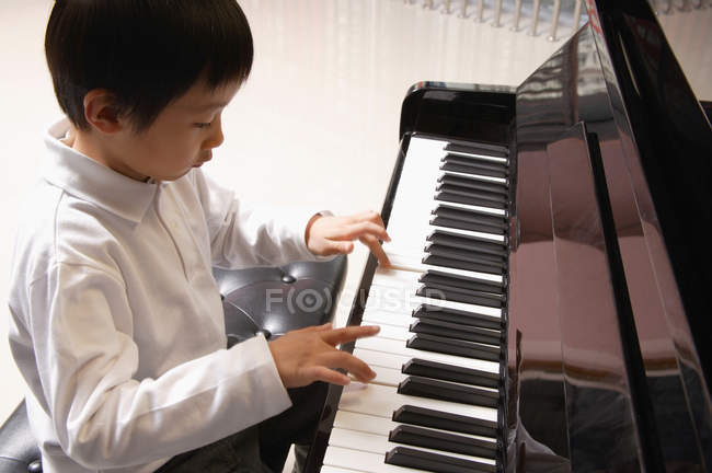 Мальчик учится играть на пианино — стоковое фото