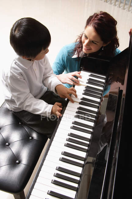 Мальчик учится играть на фортепиано с репетитором — стоковое фото