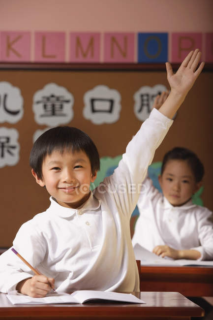 Studenti in classe alzando le mani — Foto stock