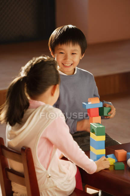 Niño y niña jugando con bloques de construcción - foto de stock