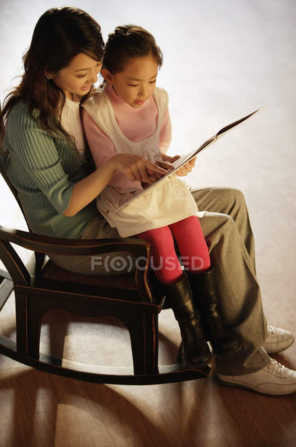 Madre e hija leyendo libro - foto de stock