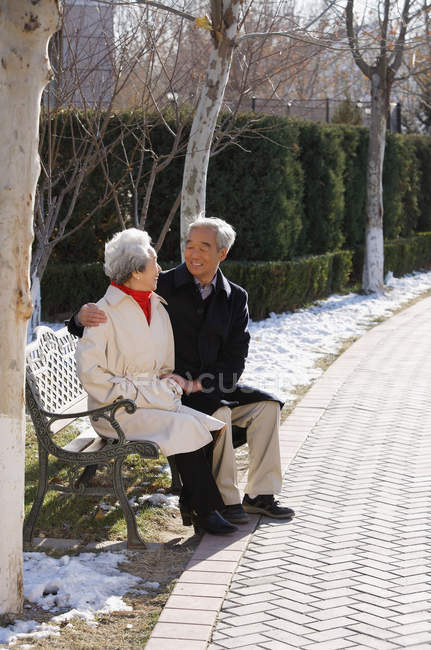 Elderly couple sitting on park bench — Stock Photo