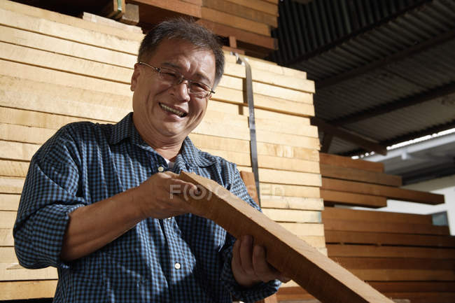 Handwerker inspiziert Holzplanke — Stockfoto
