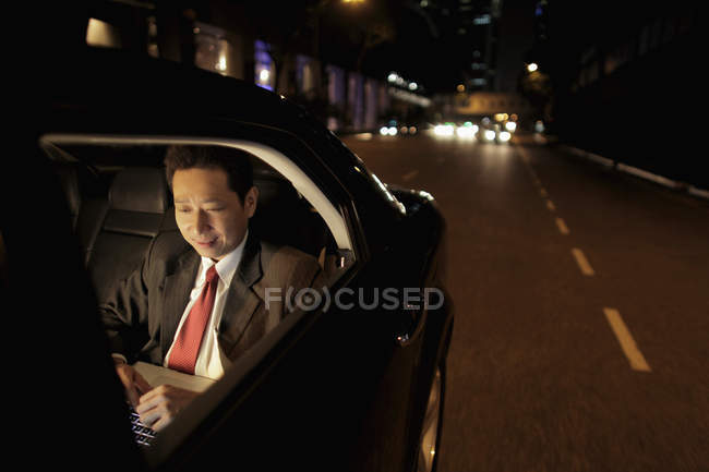 Homme d'affaires assis sur le siège arrière de la voiture — Photo de stock