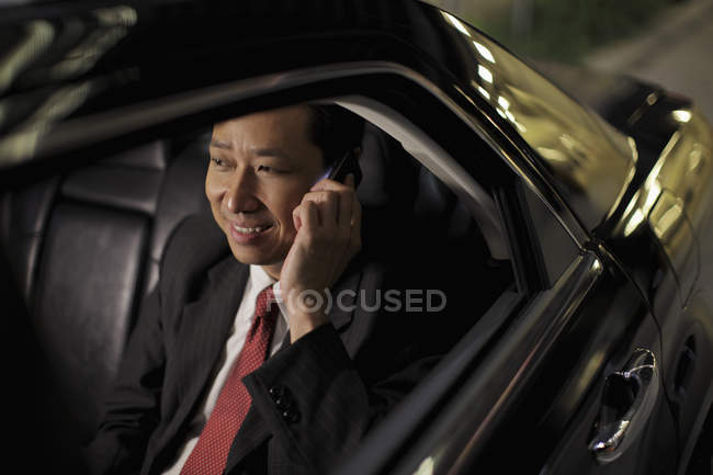 Businessman sitting in car and talking on phone — Stock Photo