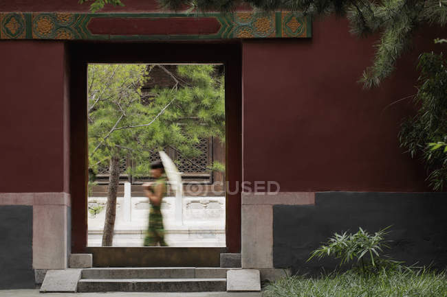 Woman walking by Chinese doorway — Stock Photo