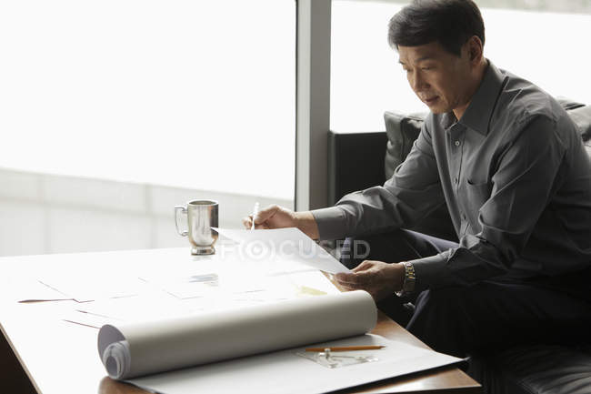 Geschäftsmann arbeitet im Büro mit Blaupausen — Stockfoto