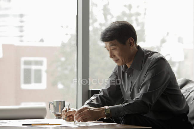 Hombre de negocios trabajando cerca de ventana - foto de stock