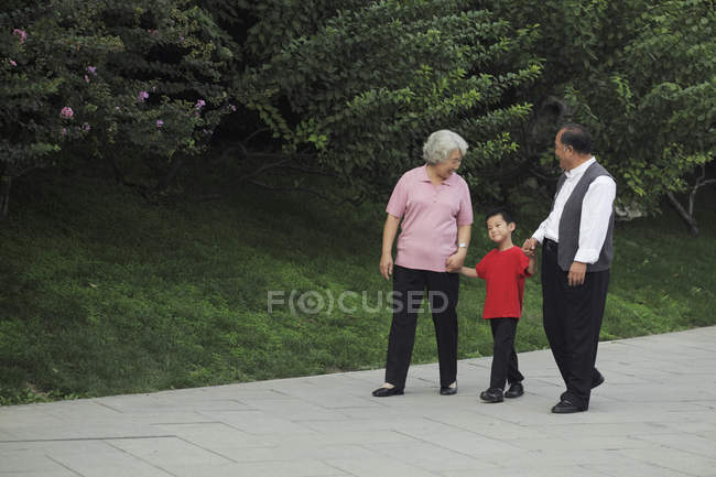 Älteres Paar geht mit Enkel spazieren — Stockfoto