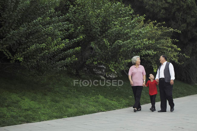 Старшая пара, идущая с внуком — стоковое фото