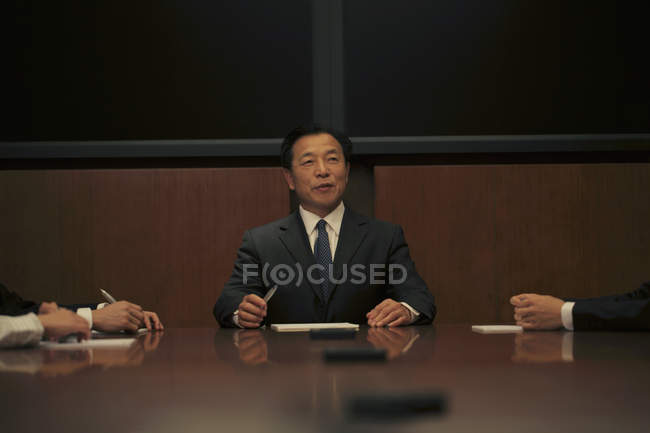 Uomo d'affari seduto a capo del tavolo — Foto stock