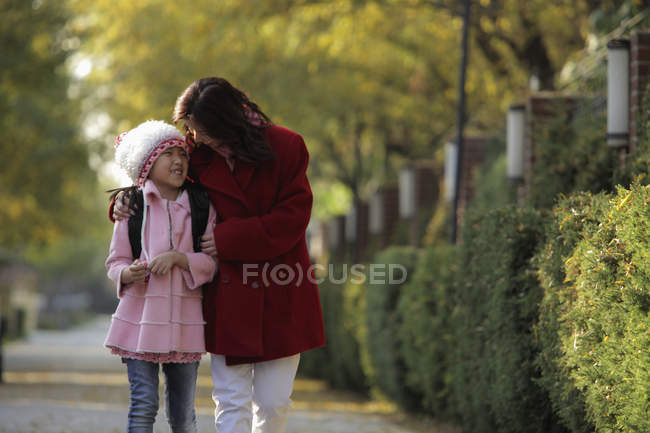 Madre e hija caminando por la calle - foto de stock