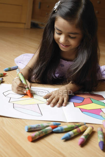 Girl lying on floor and coloring pages — Stock Photo