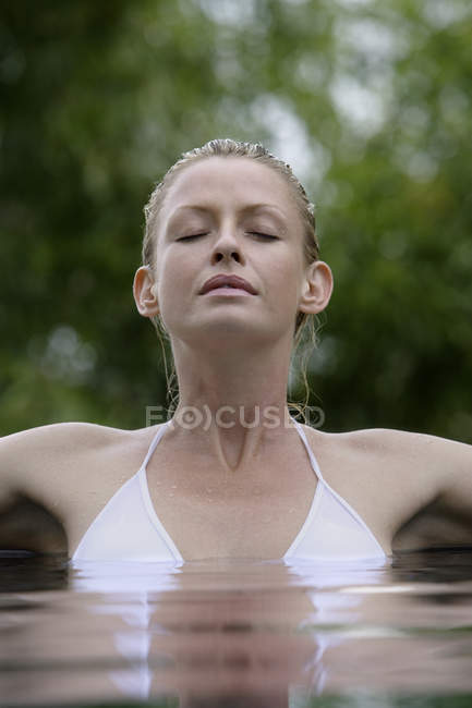 Femme dans la piscine entourée d'arbres — Photo de stock