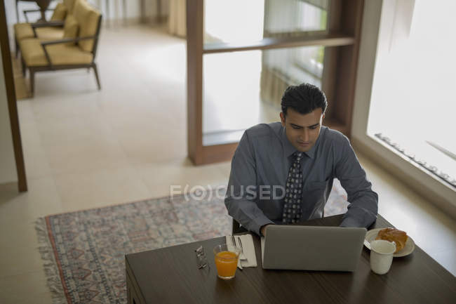 Empresario en casa usando laptop - foto de stock