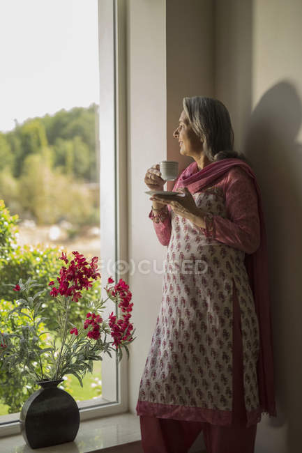 Mulher de pé na janela — Fotografia de Stock