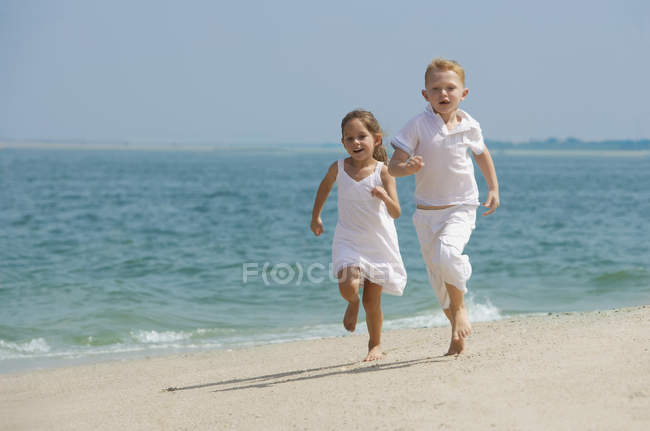 Glückliche Kinder laufen am Strand — Stockfoto