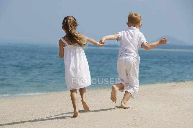 Glückliche Kinder laufen am Strand — Stockfoto
