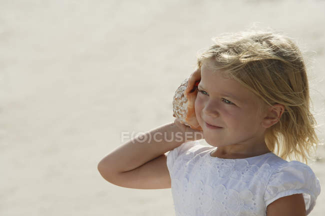 Girl listening to seashell — Stock Photo