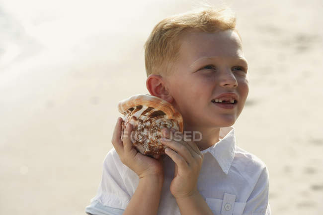 Junge hört Muschel zu — Stockfoto