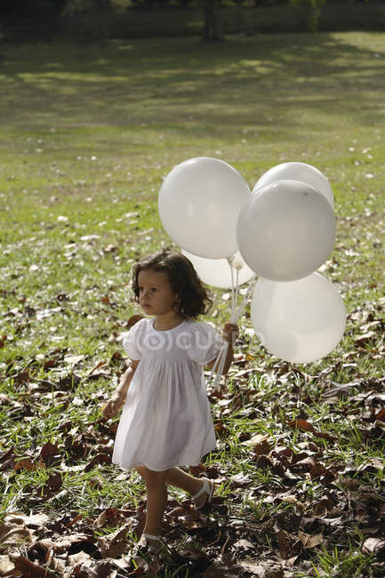 Chica en el parque, con globos - foto de stock