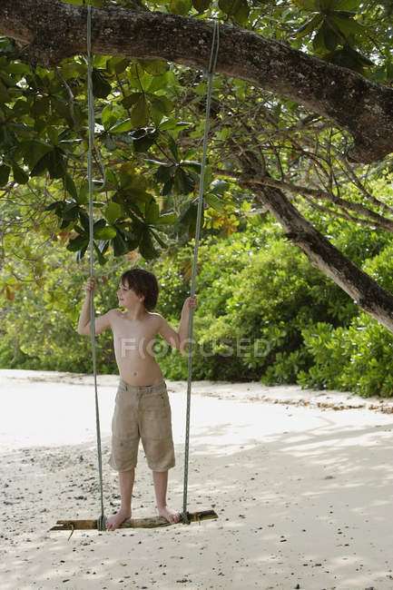 Мальчик стоит на качелях — стоковое фото