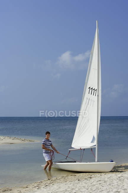Homme avec voilier à la plage — Photo de stock